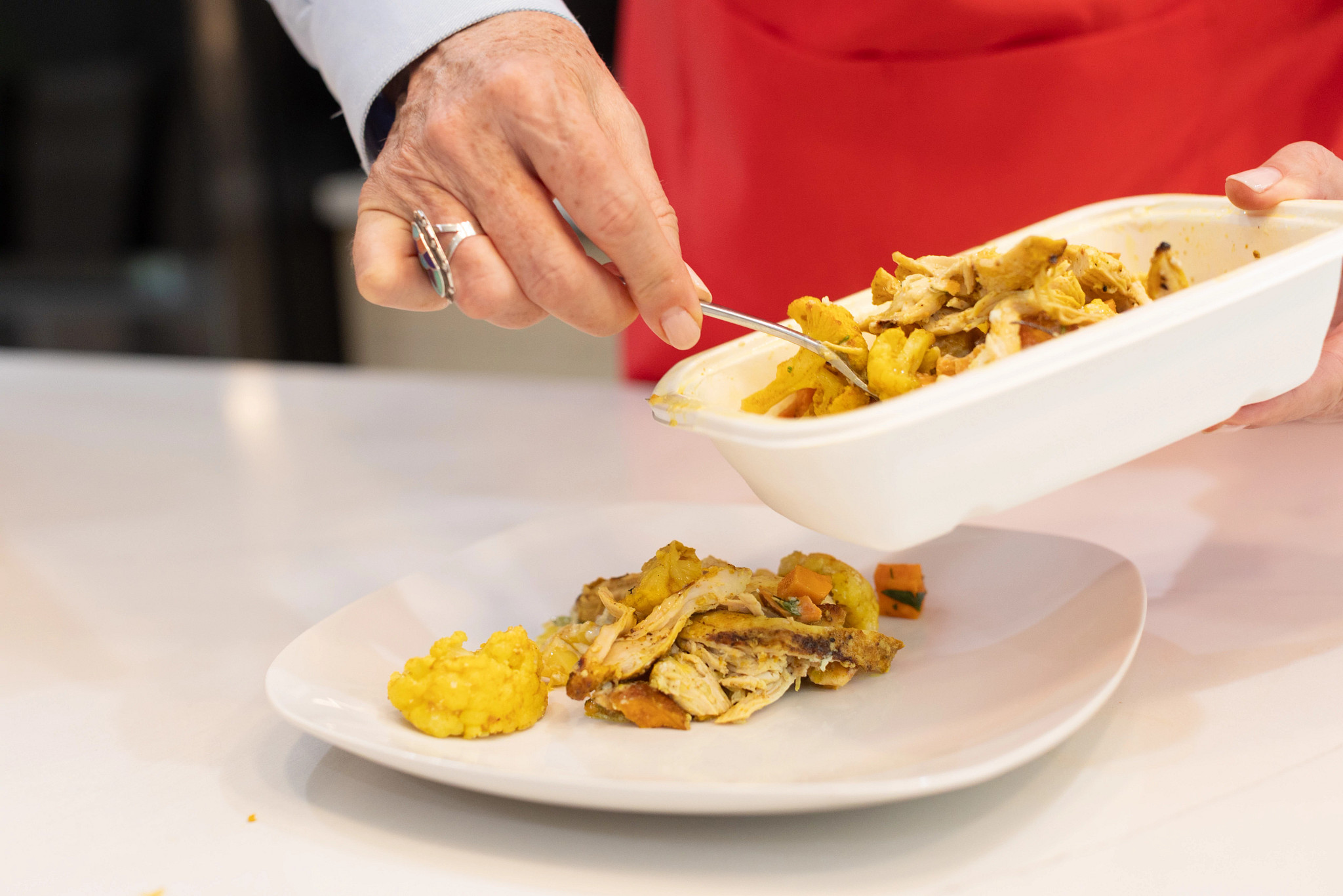 A person plating a CookUnity meal from the packaging