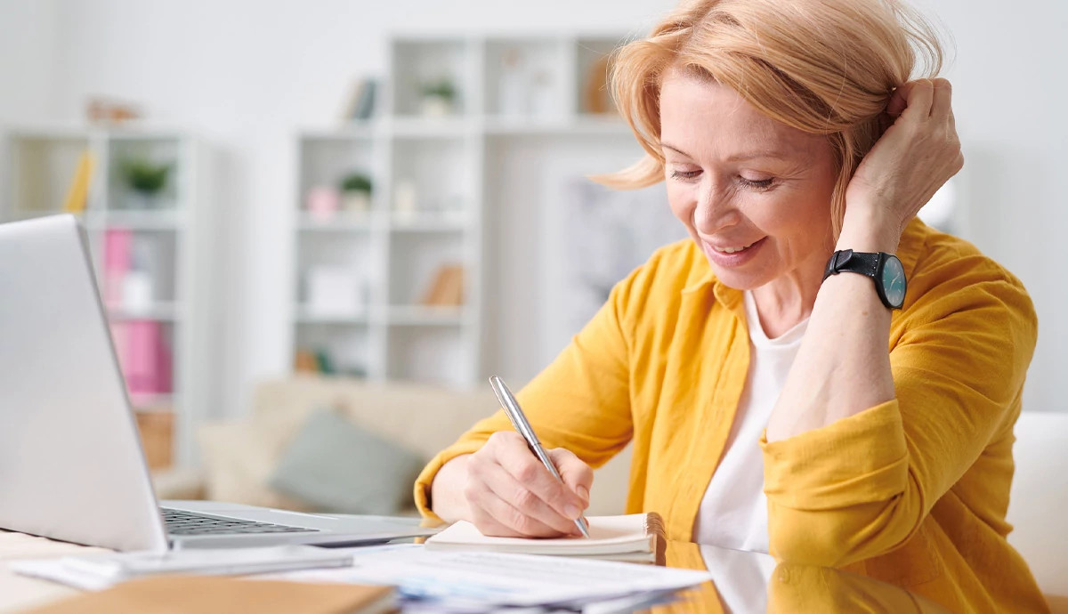 A woman writes something down in a notebook.