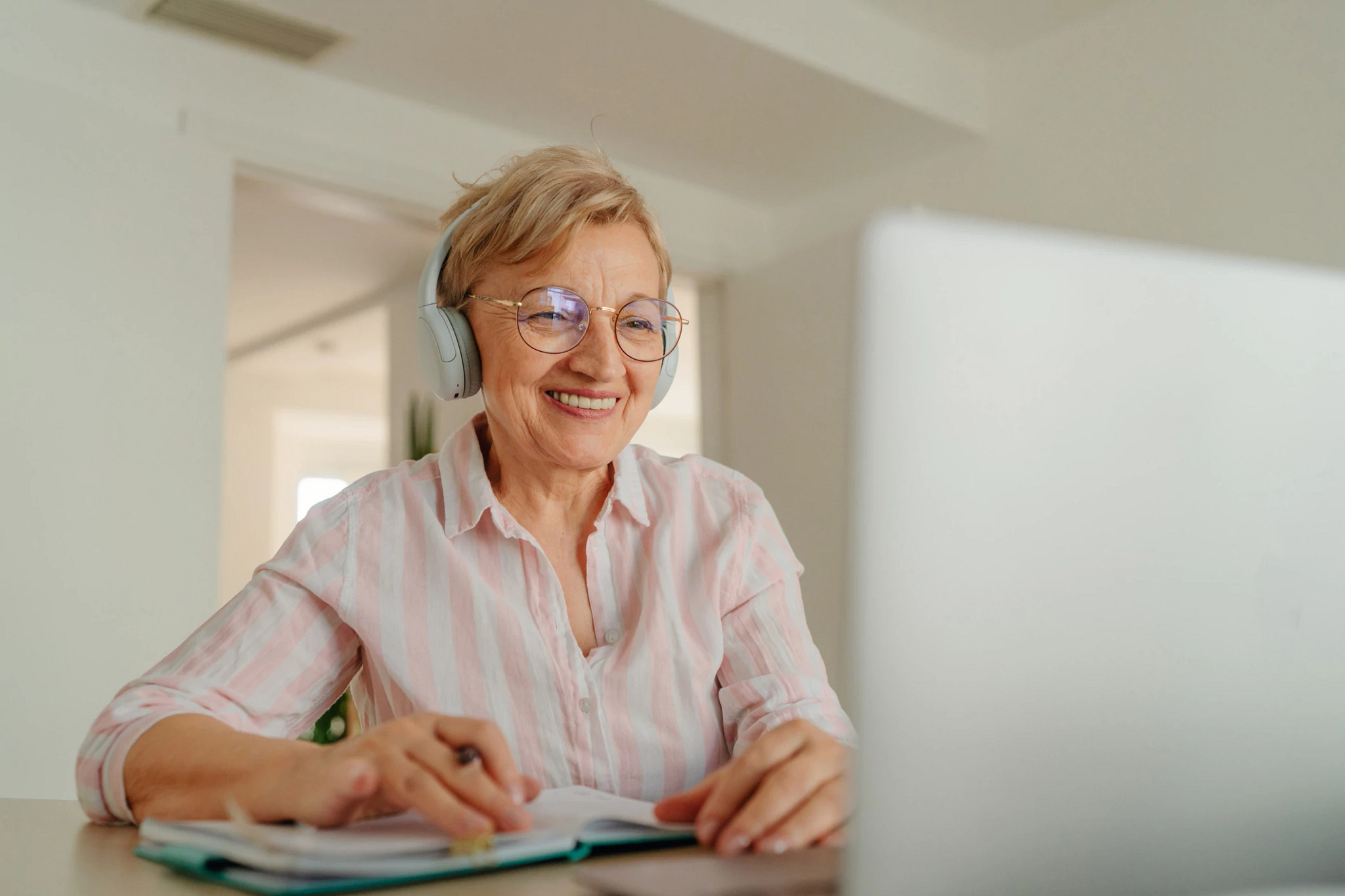 a woman on a computer, wearing headphones on a webinar.