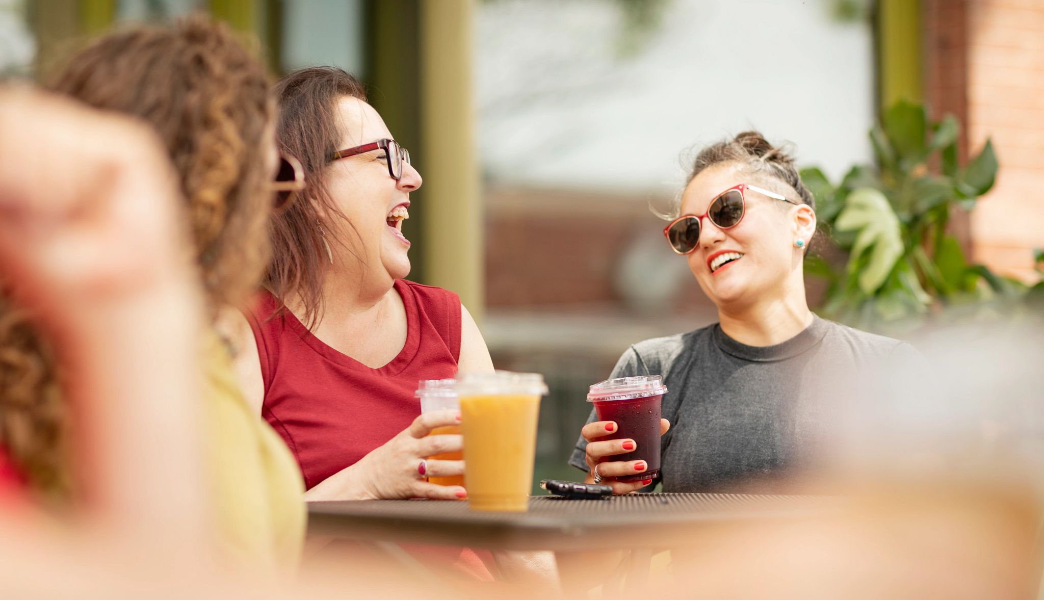 Friends celebrating on a restaurant patio with drinks and laughing Friends celebrating on a restaurant patio with drinks and laughing