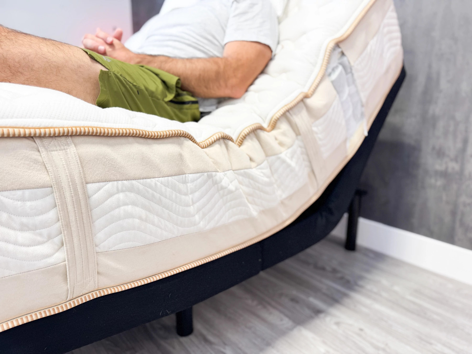 A man sitting on a mattress that’s adjusted with an adjustable base