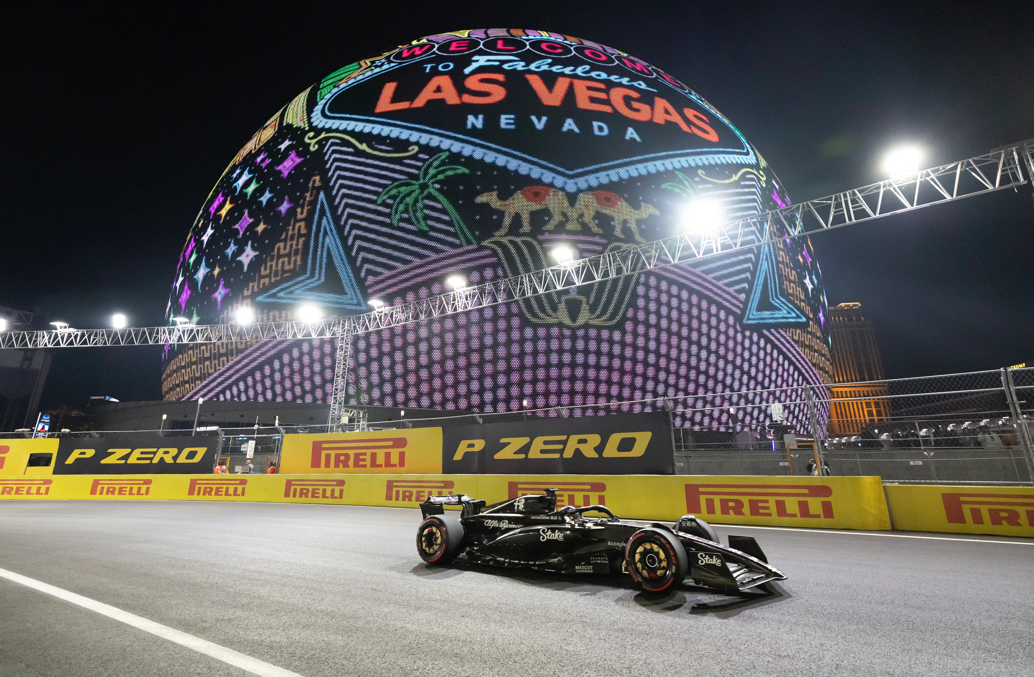 Formula 1 racecar on track; big sphere that says Welcome to Fabulous Las Vegas Nevada in background