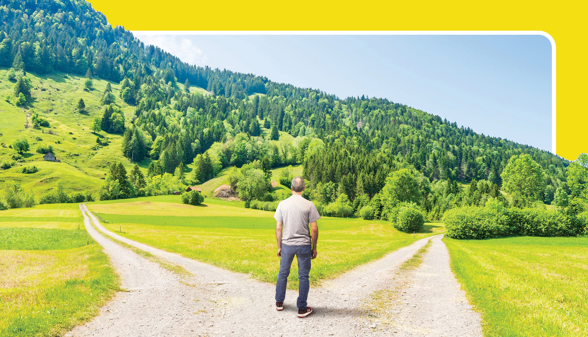 a man standing in a field facing a fork in the road