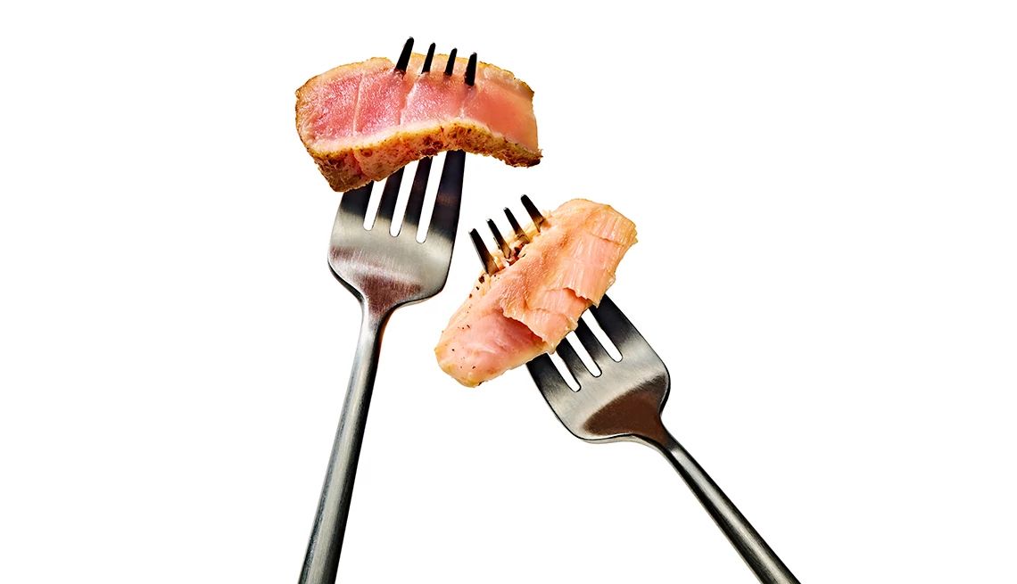 Two forks, one with a piece of Atlantic salmon on it, one with a piece of tuna on it