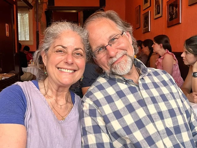 Couple embracing at a restaurant table while sharing a meal together.