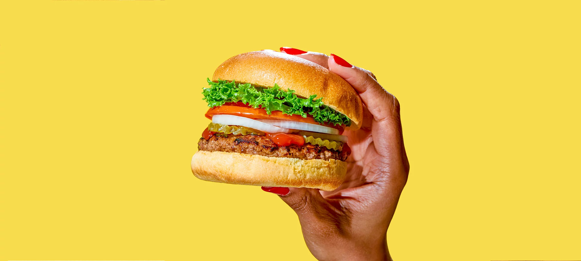 African American woman's hand holding a delicious looking burger