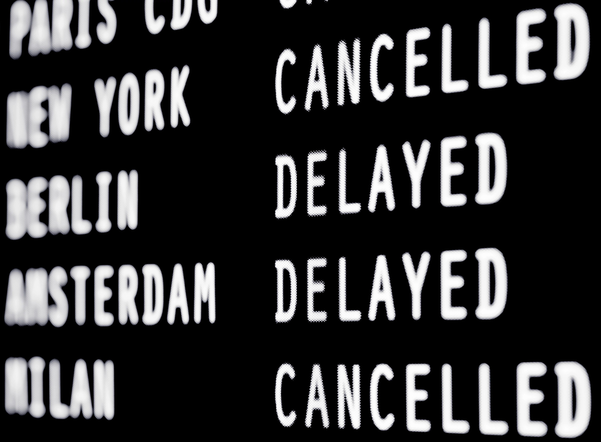 an airport board showing flight delays and cancellations