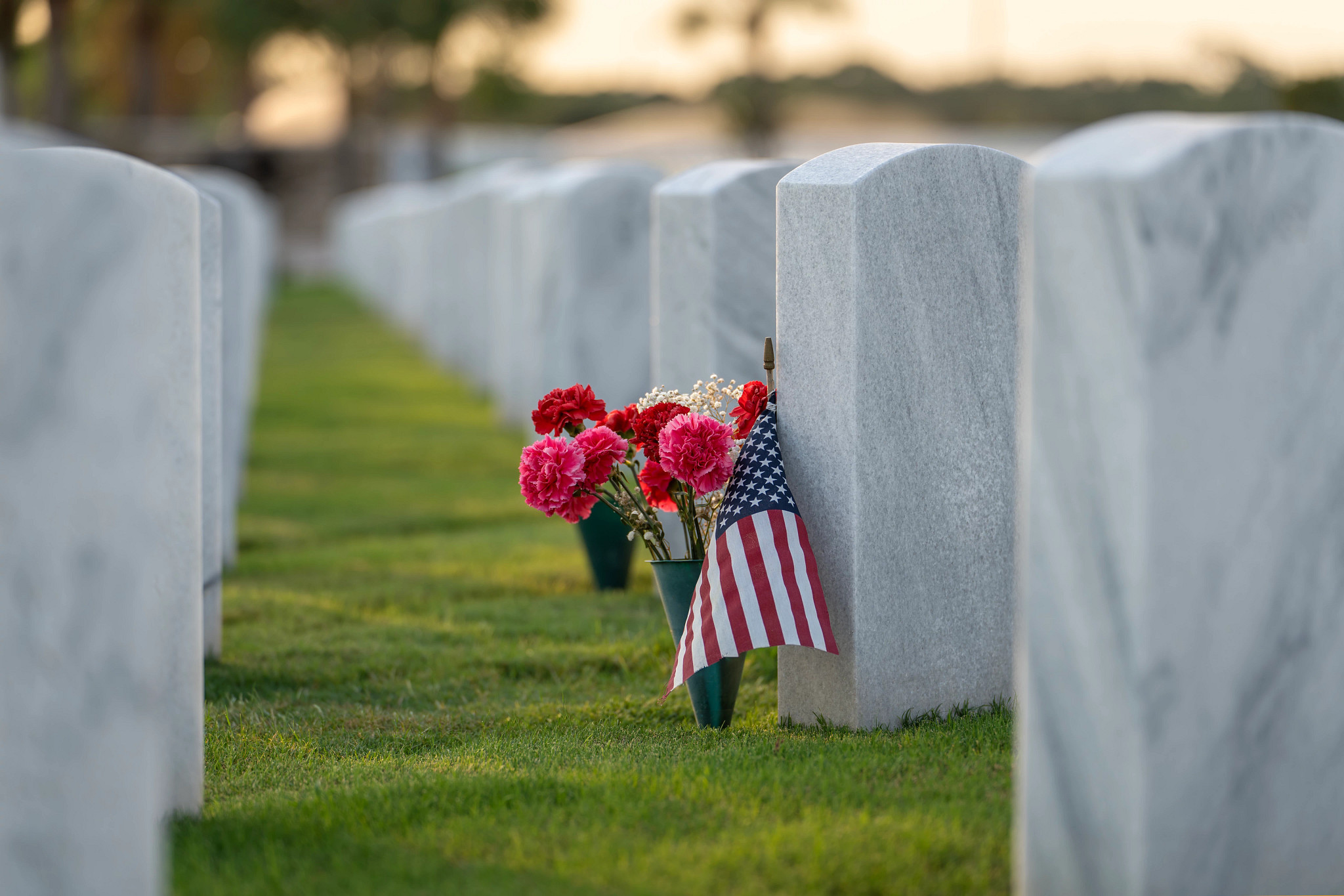Sarasota National Cemetery with rows of white tomb stones with flowers and USA flags on green grass