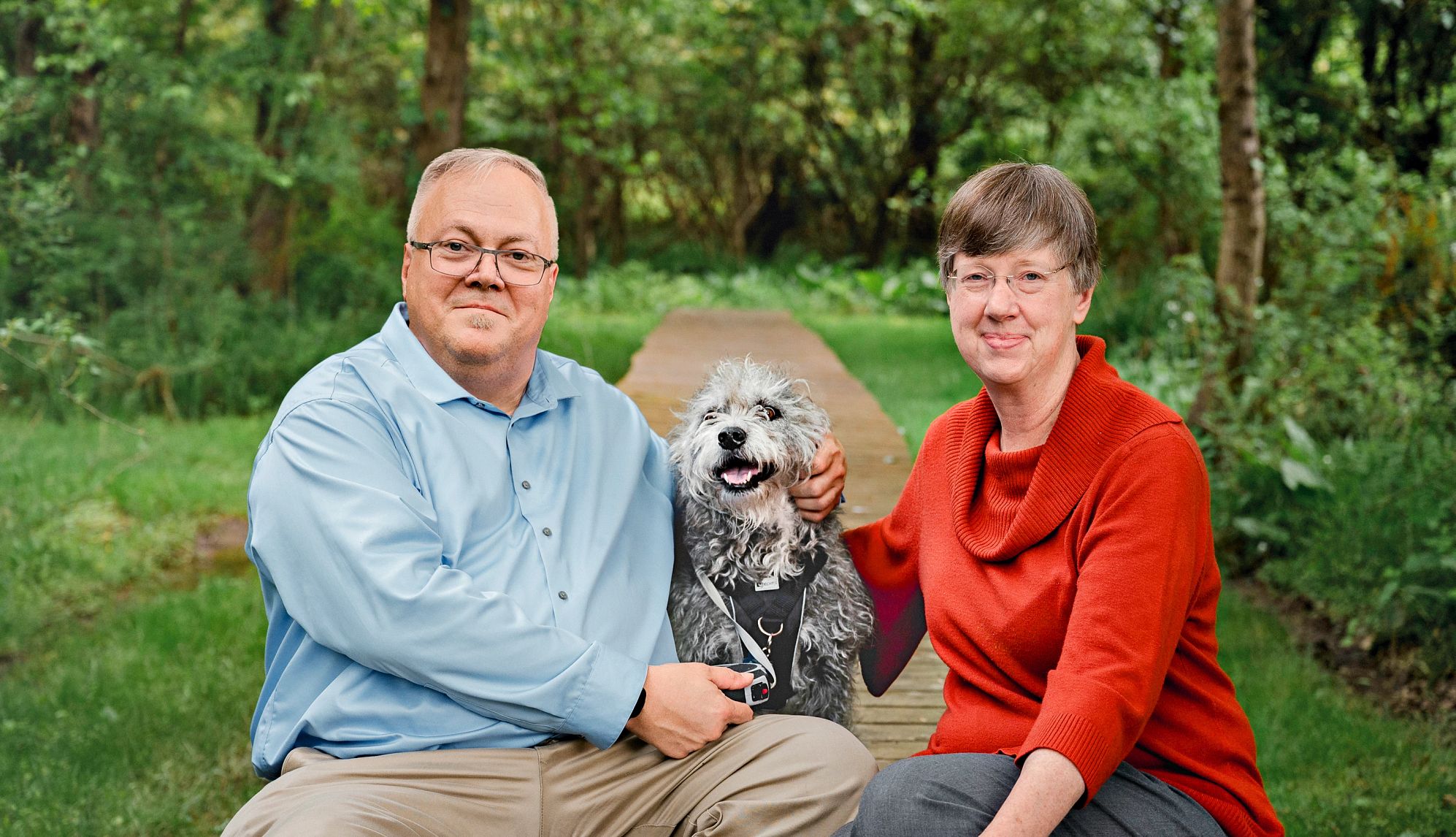 Keep the life insurance or cash out the policy? Steven and Kathryn Burtch sitting outside with dog between them and trees around them