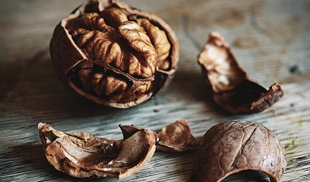 A close-up view of a cracked walnut on wood
