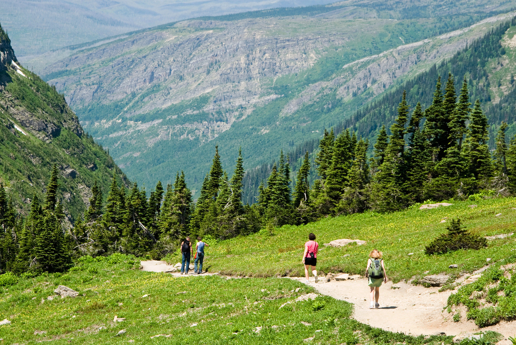 Hikers on a trail surrounded by green mountains 