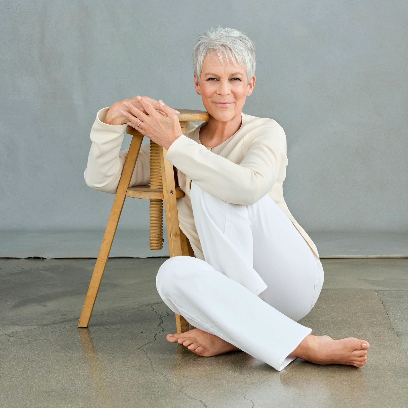 The Liberation of Jamie Lee Curtis jaime lee curtis sitting on the floor with her arms around a wooden stool