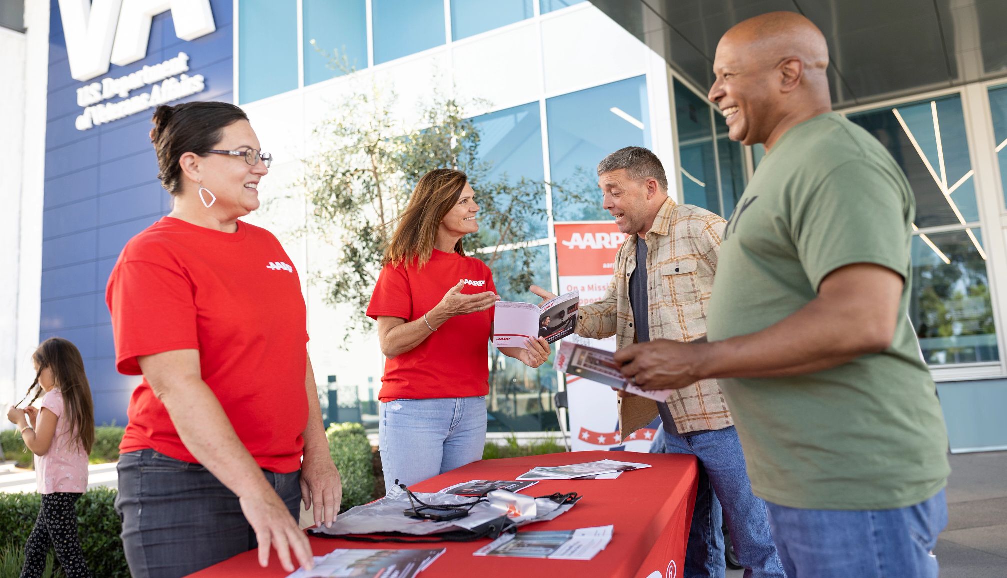 AARP Volunteers volunteers meet with two veterans outside of a veterans affairs medical facility