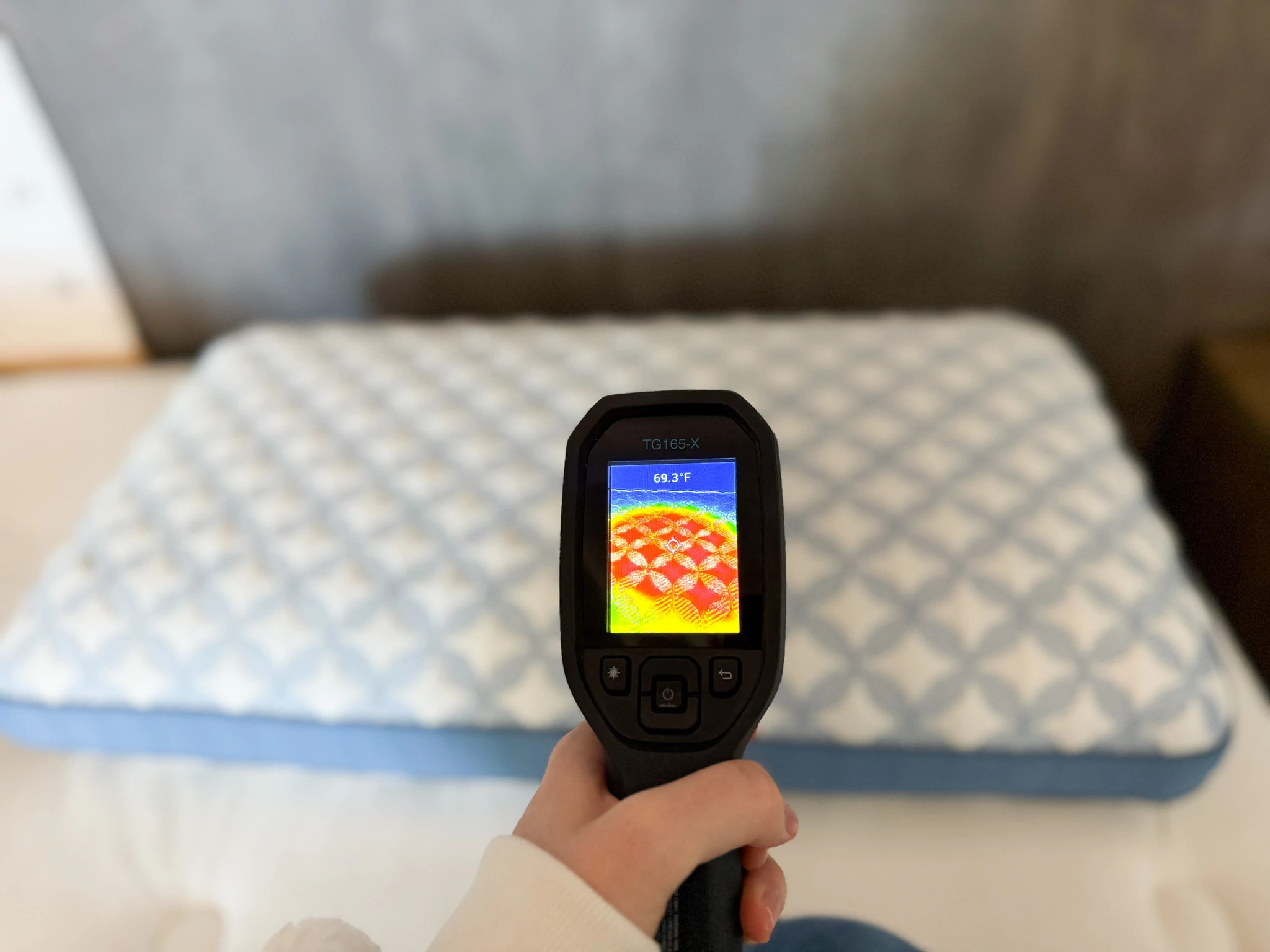 A hand holding a temperature gun pointing at the Helix Cooling Memory Foam Pillow