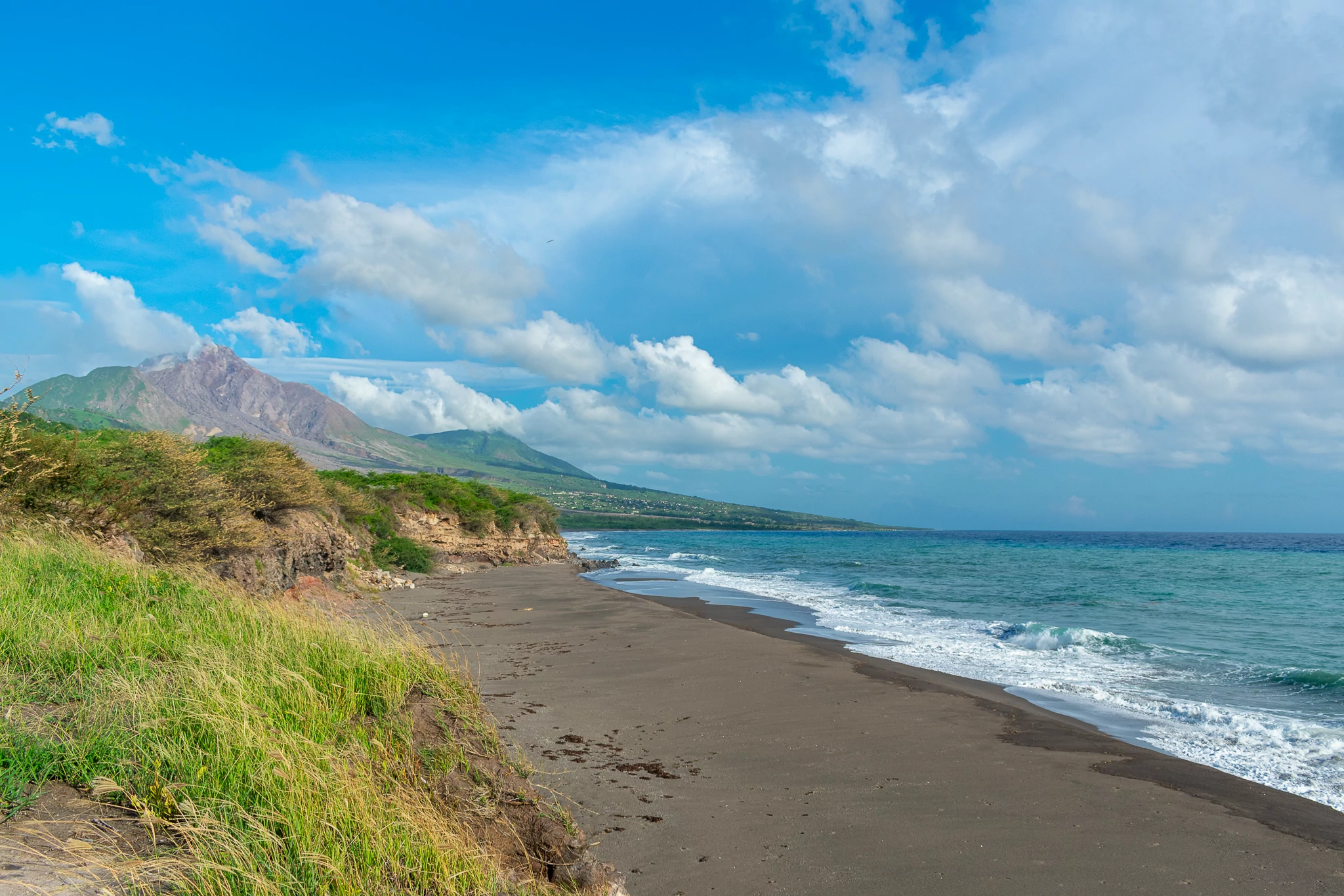 an empty beach with mountains in the background