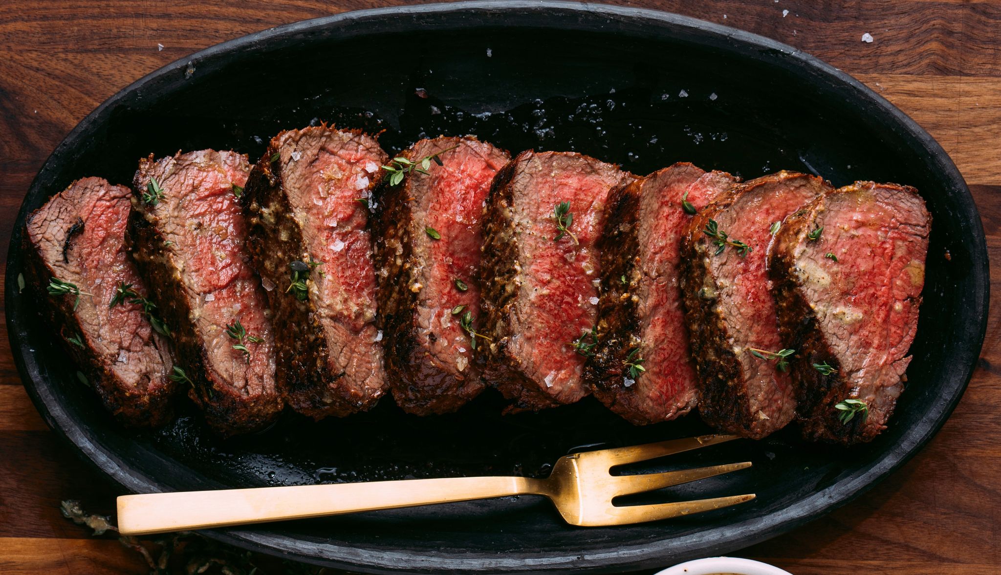 Whole beef tenderloin Beef tenderloin cut into slices with fork next to it in dish