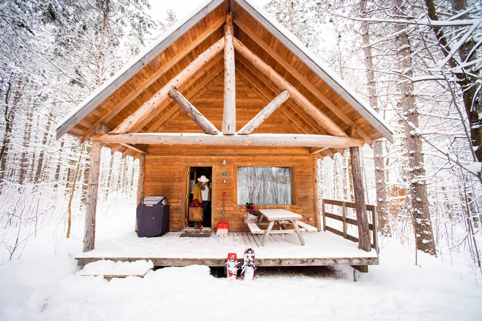 a woman walking out of a snow covered cabin