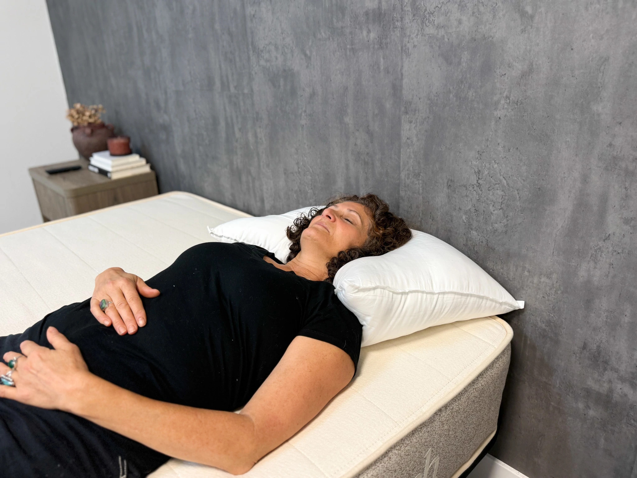A woman lies on a mattress on her back, with her head resting on a Buffy Cloud Pillow