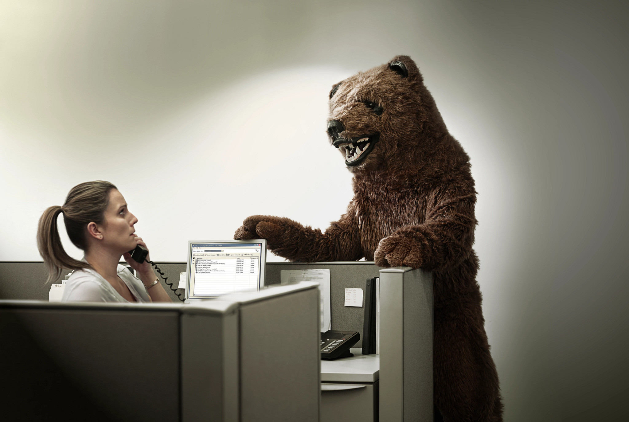 woman at work in cubicle with boss in bear costume standing over her desk