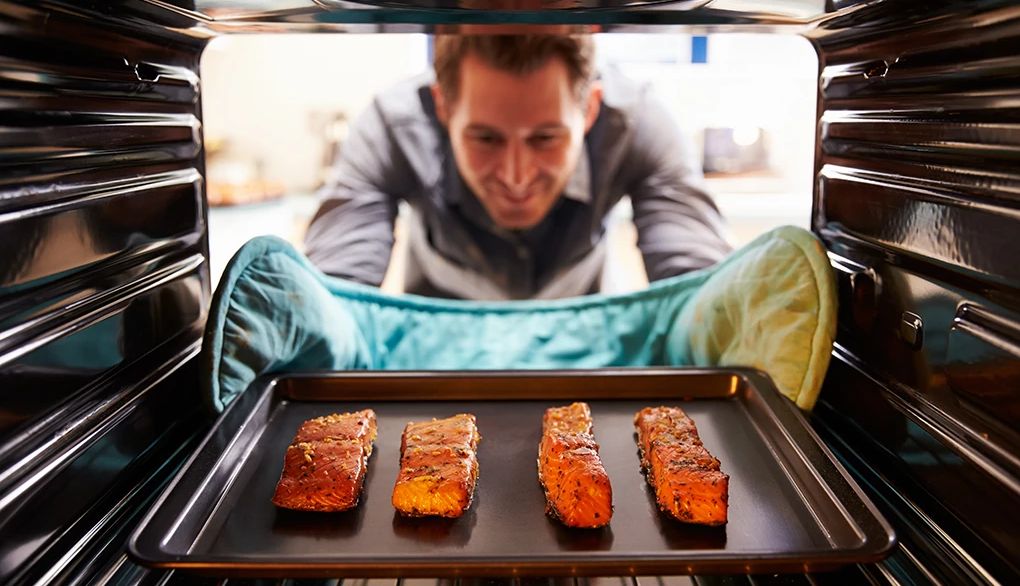 Eating salmon may help support brain health A man taking a tray of salmon fillets out of the oven