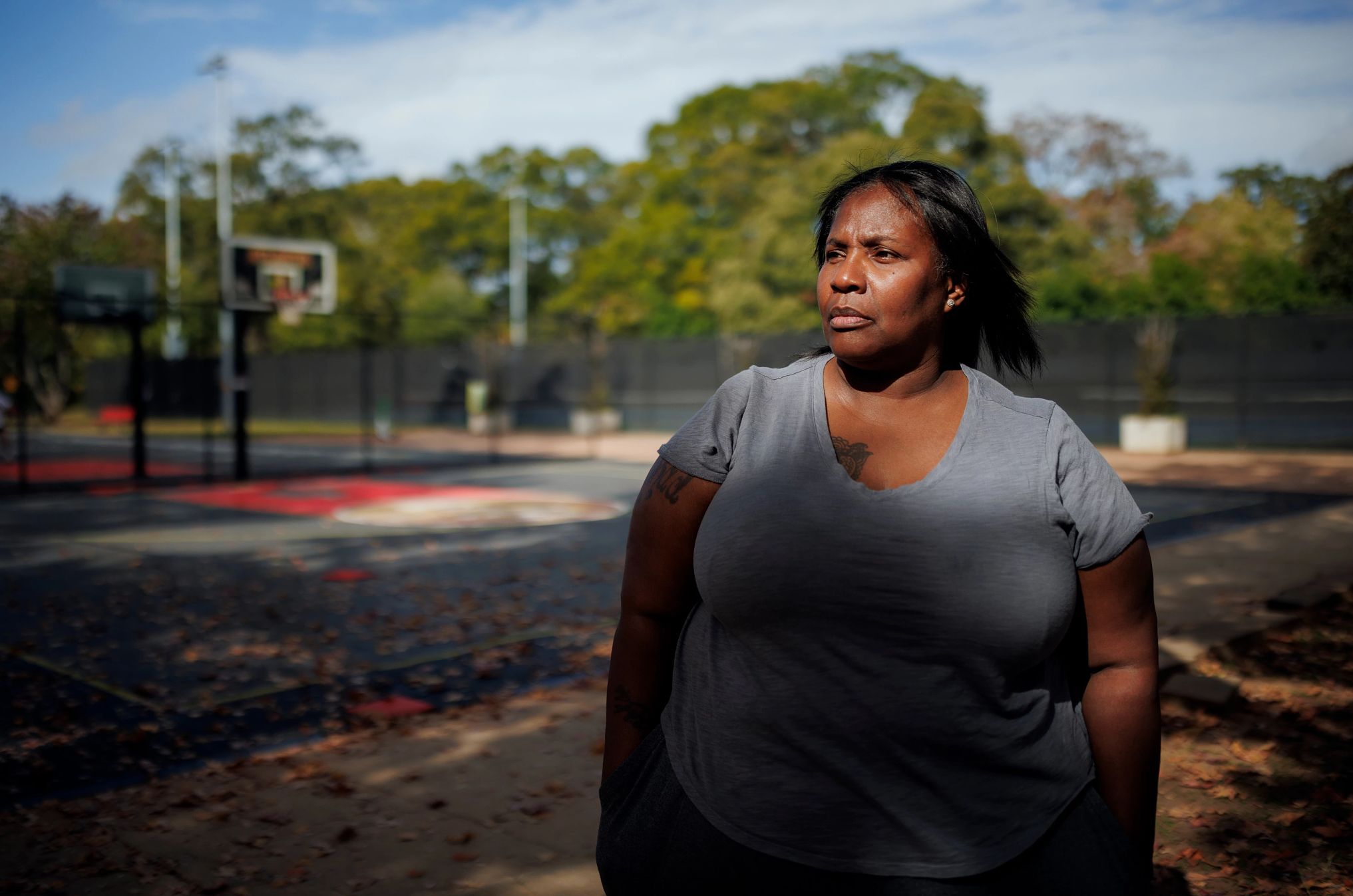 Tia Willingham a woman looks off into the distance in front of a basketball court
