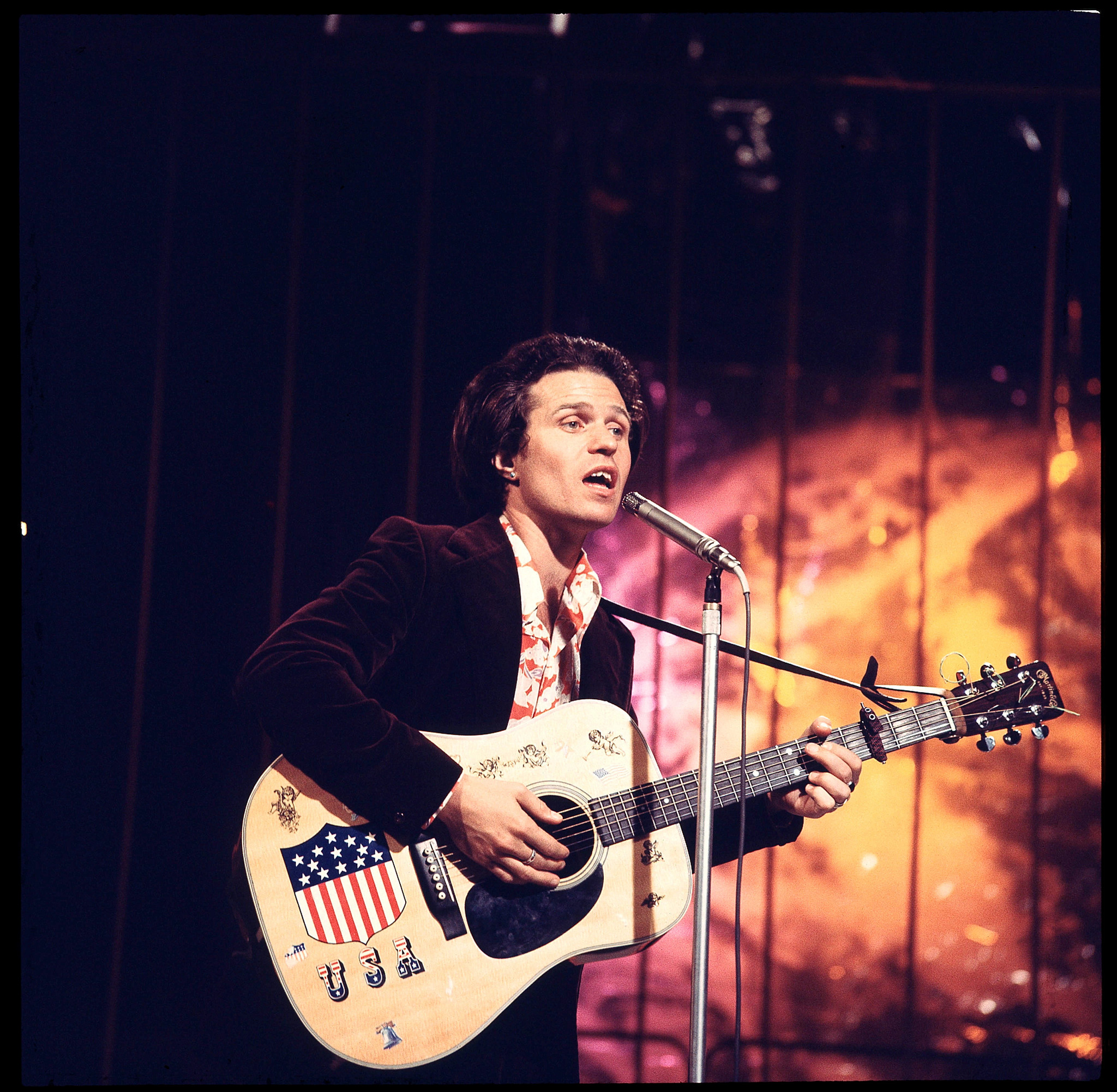 country joe mcdonald performing onstage with a guitar