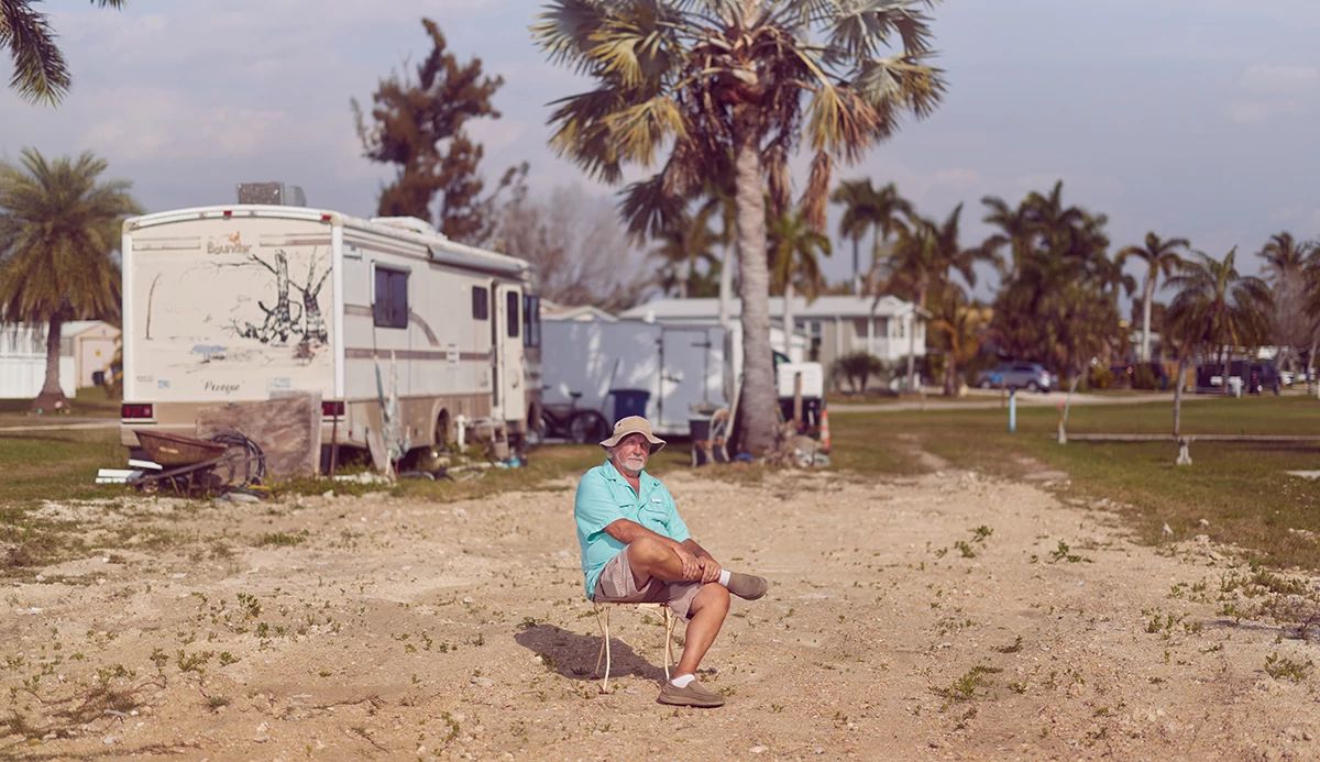 A man in turquoise shirt sitting outdoors in a chair