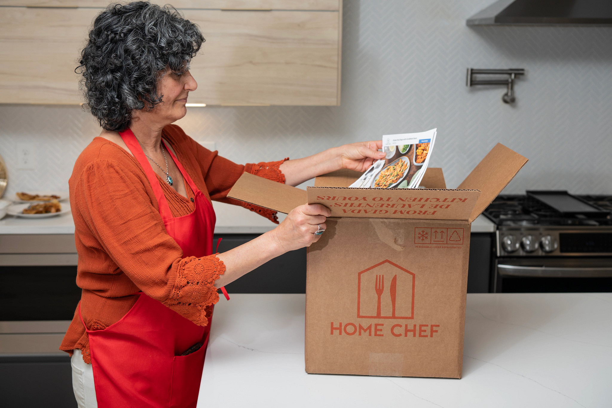 An older adult woman opening her Home Chef meal kit delivery
