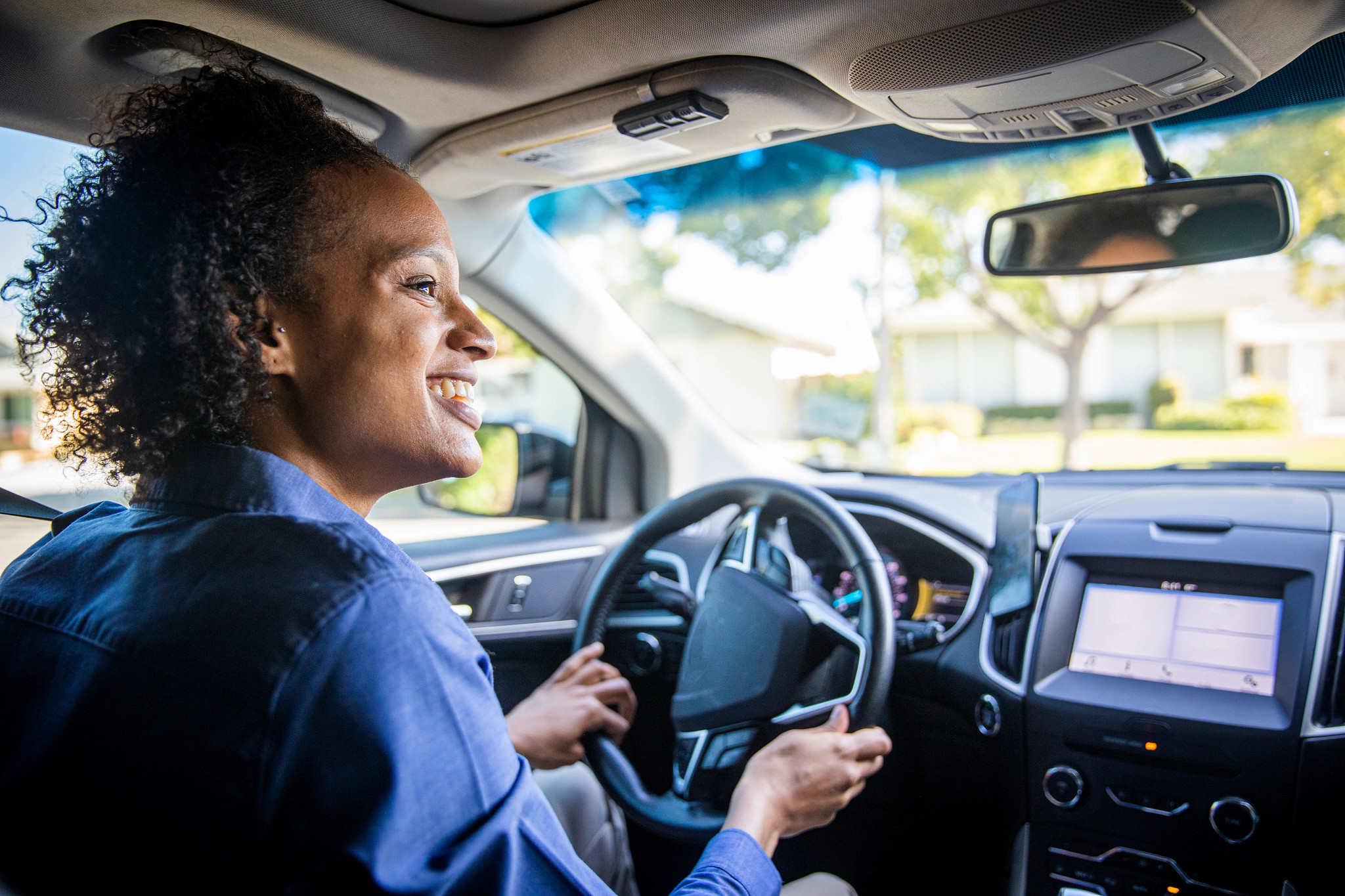 a smiling woman driving a car