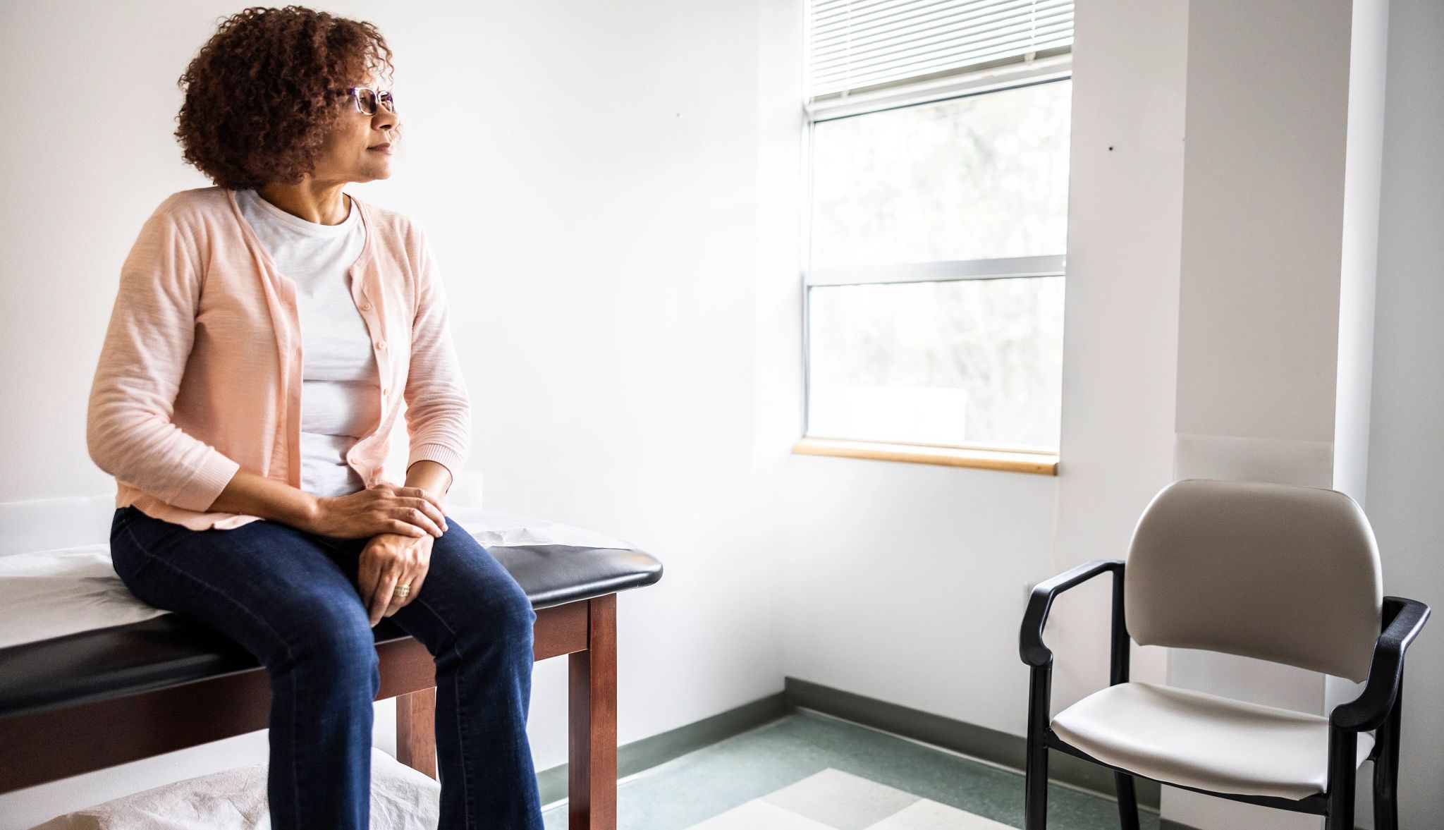 Mujer mayor sentada en un camilla en una oficina médica.
