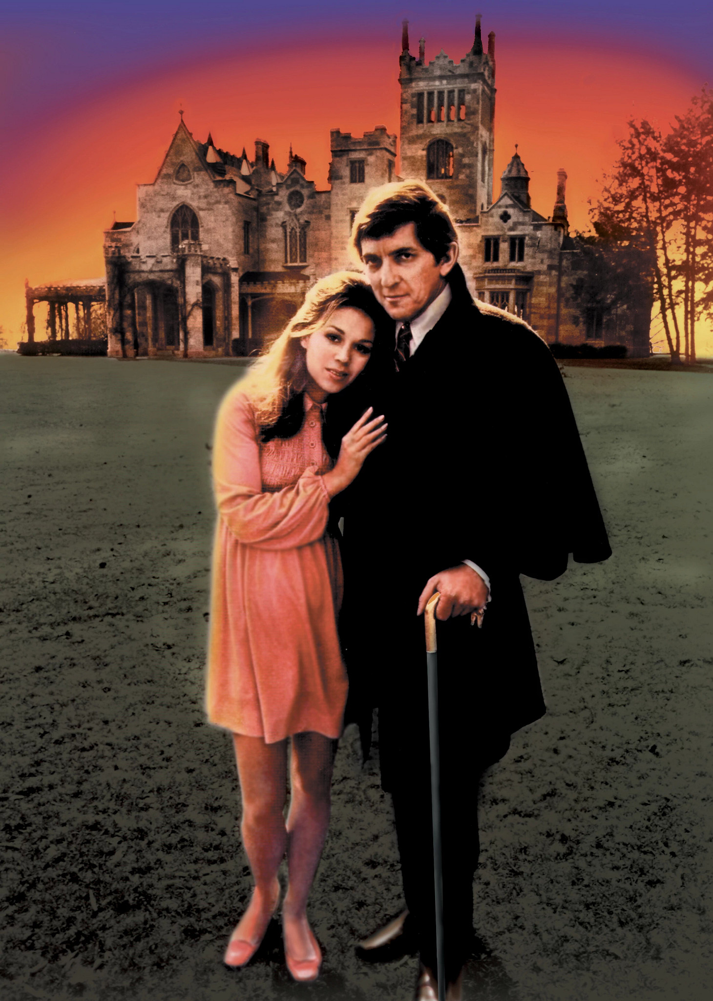 Kathryn Leigh Scott and Jonathan Frid stand together in portrait in front of a historic gothic-style estate, illuminated by a vivid sunset sky