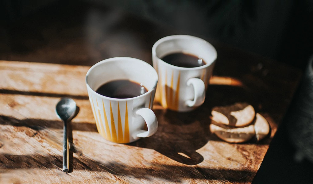 A close-up view of two mugs of coffee on a table