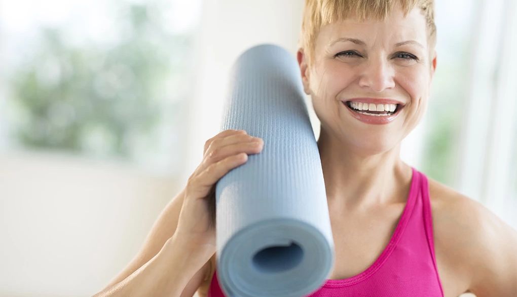 Yoga can be beneficial to our brain A woman holding a yoga mat on her shoulder