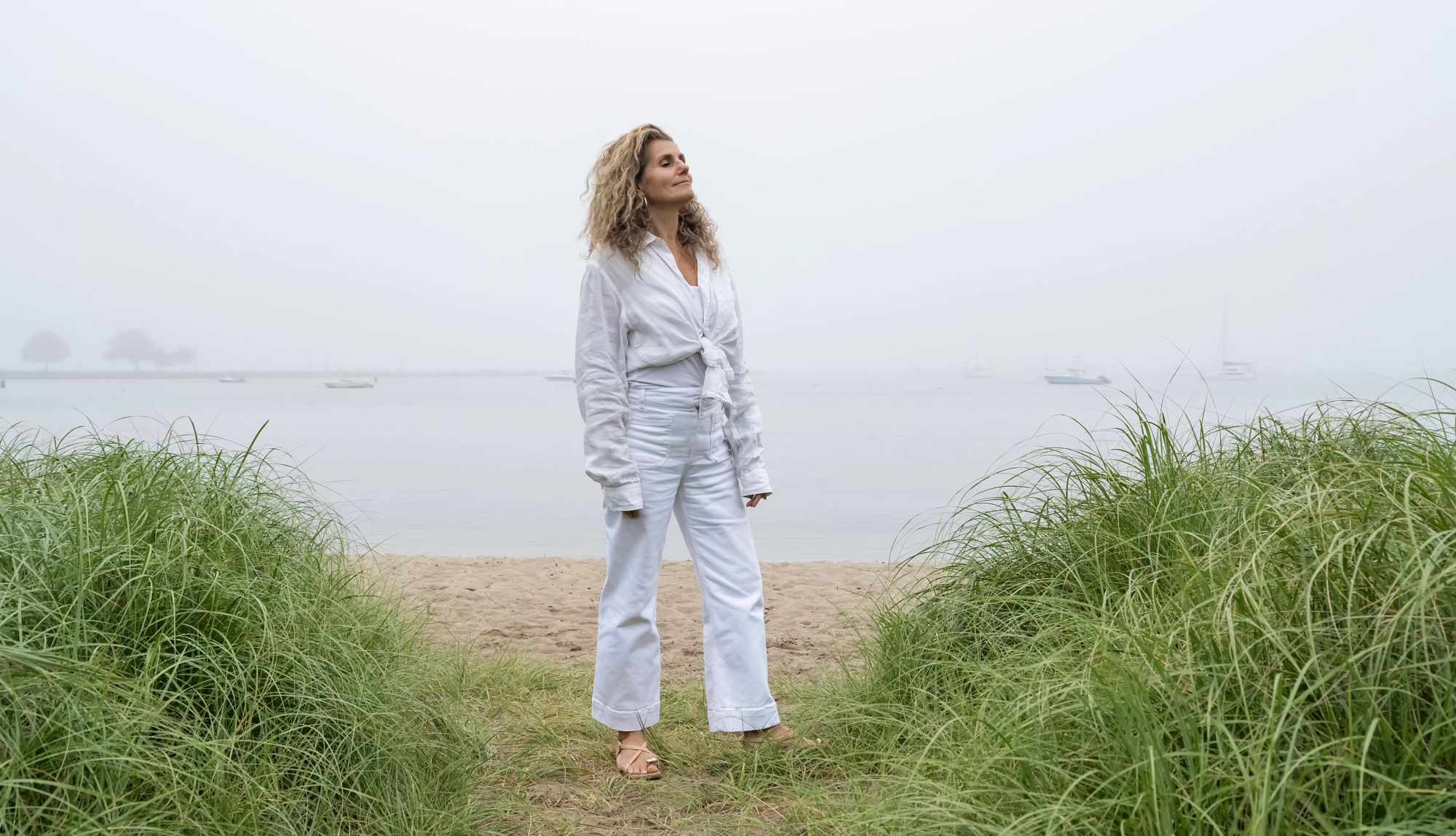 My Biggest Retirement Mistake a woman stands on the beach with her eyes closed and face turned up