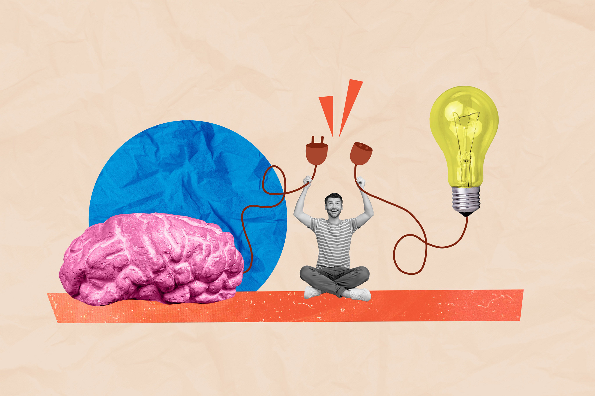 A man sitting and holding up unplugged wires that would connect a brain with a lightbulb.