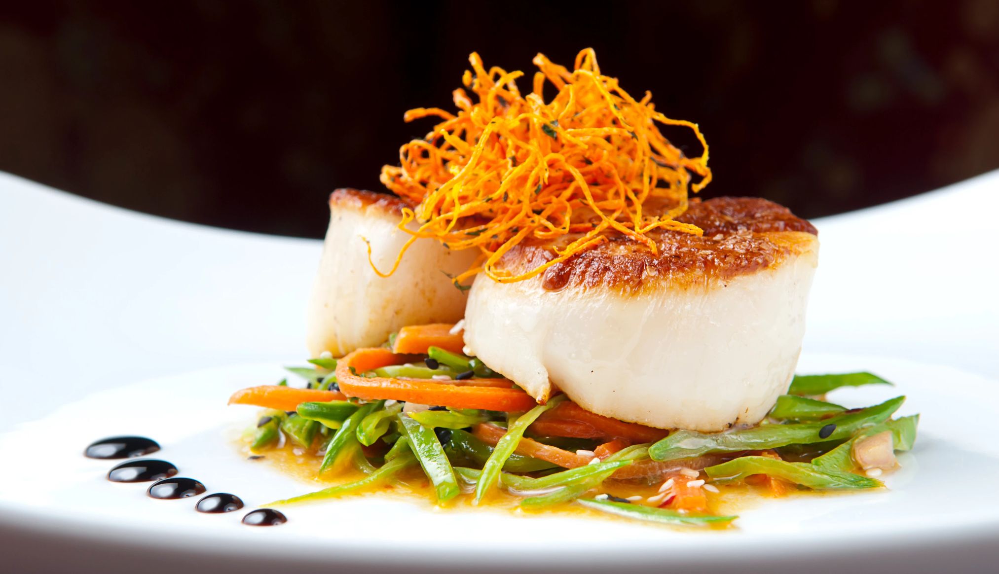 Dishes to Skip When Dining Out A photo shows seared Scallops on a bed of vegetables