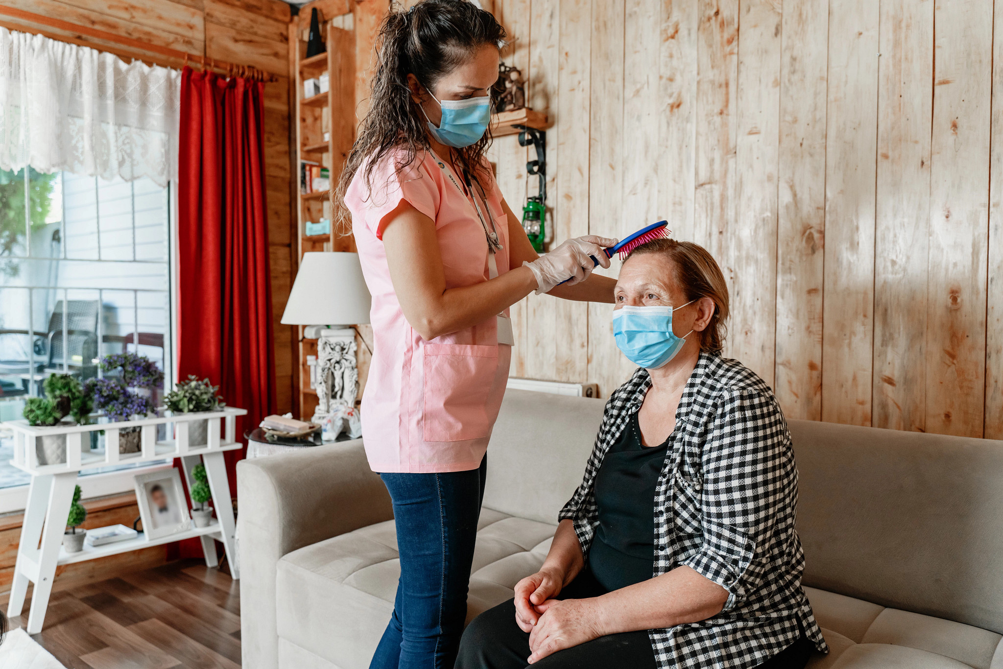 home carer helping senior woman get dressed in her living room