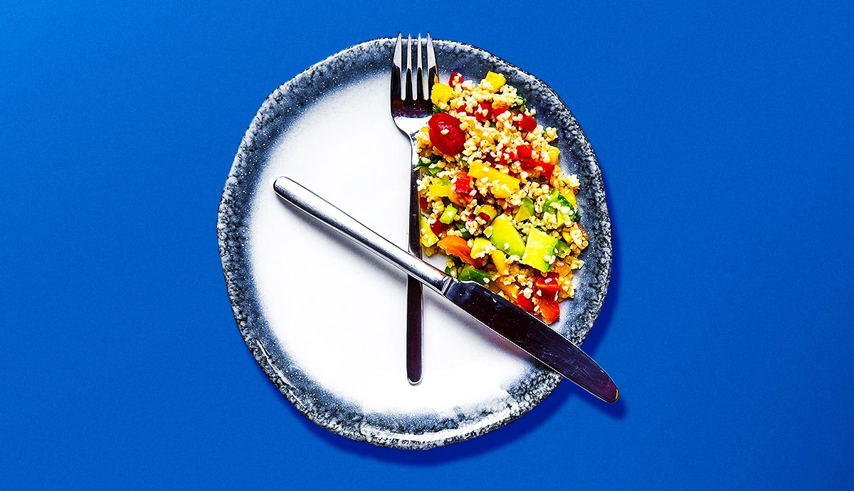 a top down view of a plate with a small amount of food and utensils arranged to look like a clock