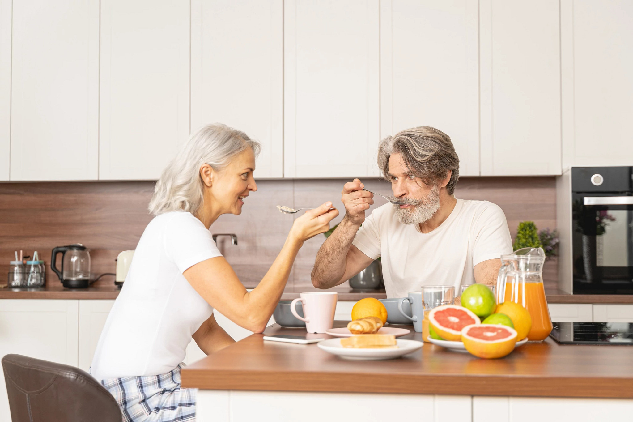 Smiling female and her husband eating porridge for breakfast