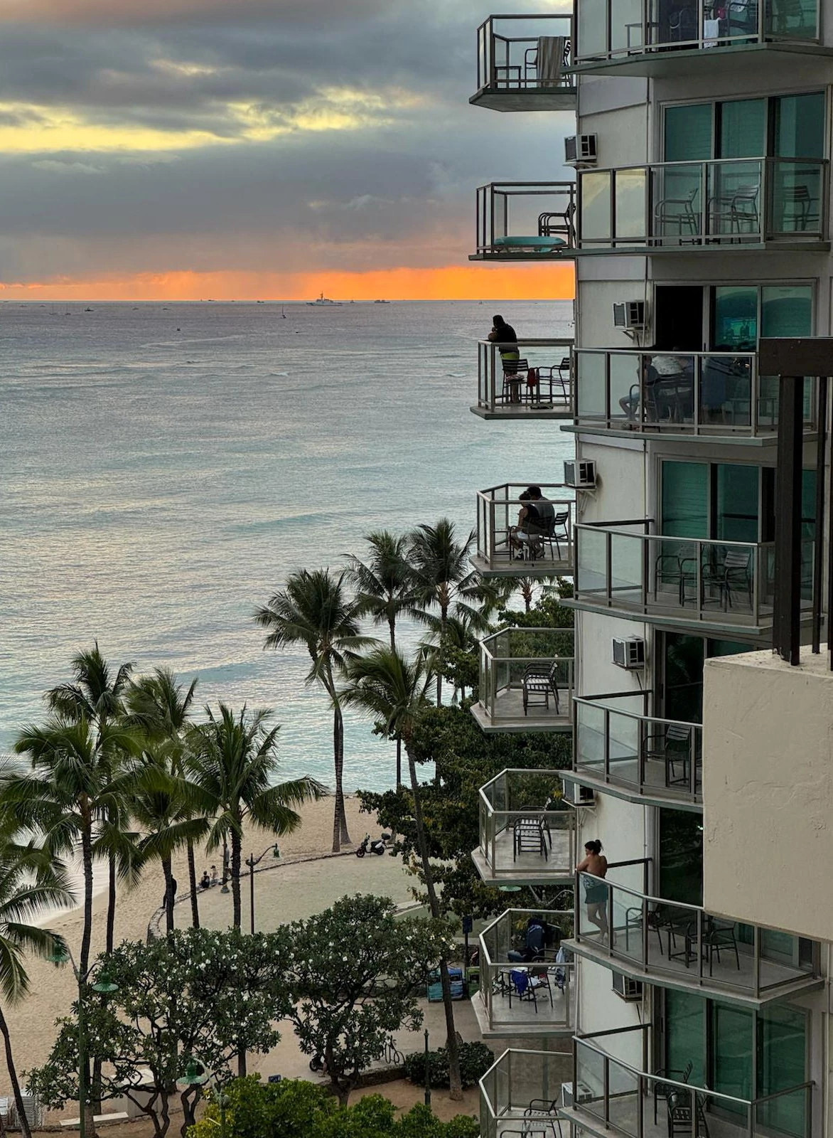 A person standing on a balcony overlooking the ocean