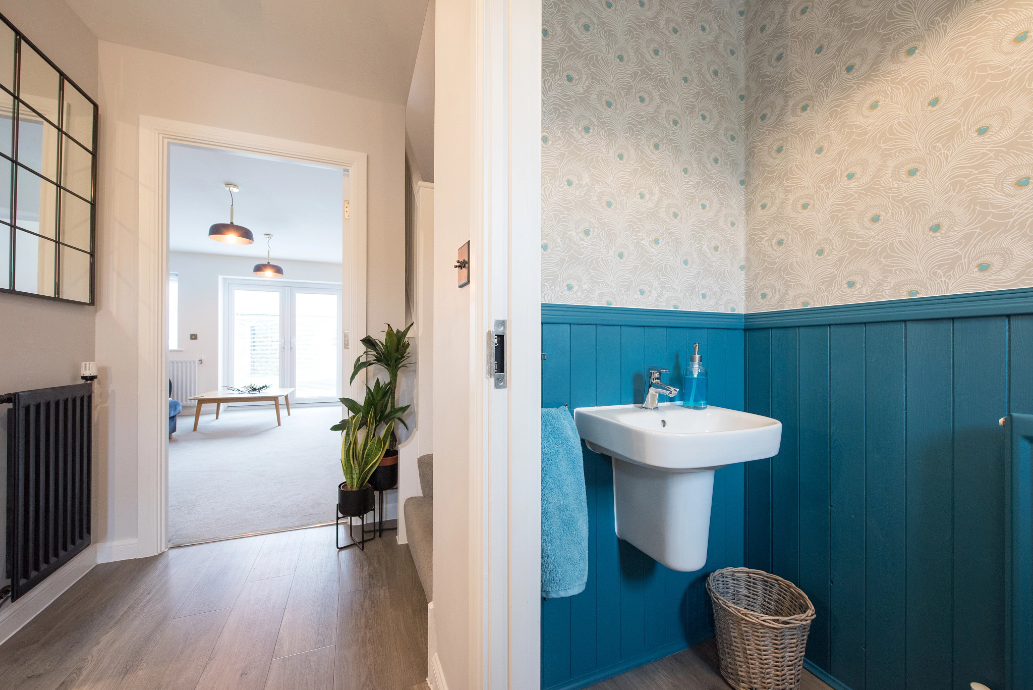 bathroom with panelling painted blue and peacock feather pattern wallpaper