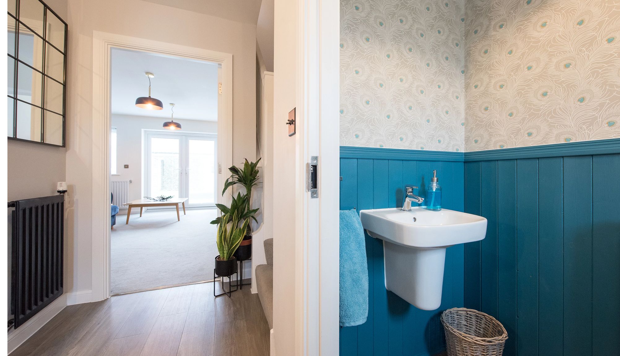 cuarto de baño con paneles azules y papel pintado con motivos de plumas de pavo real