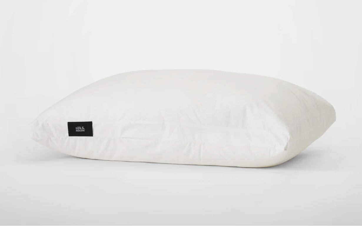 The Silk & Snow Adjustable Pillow lying on a white surface