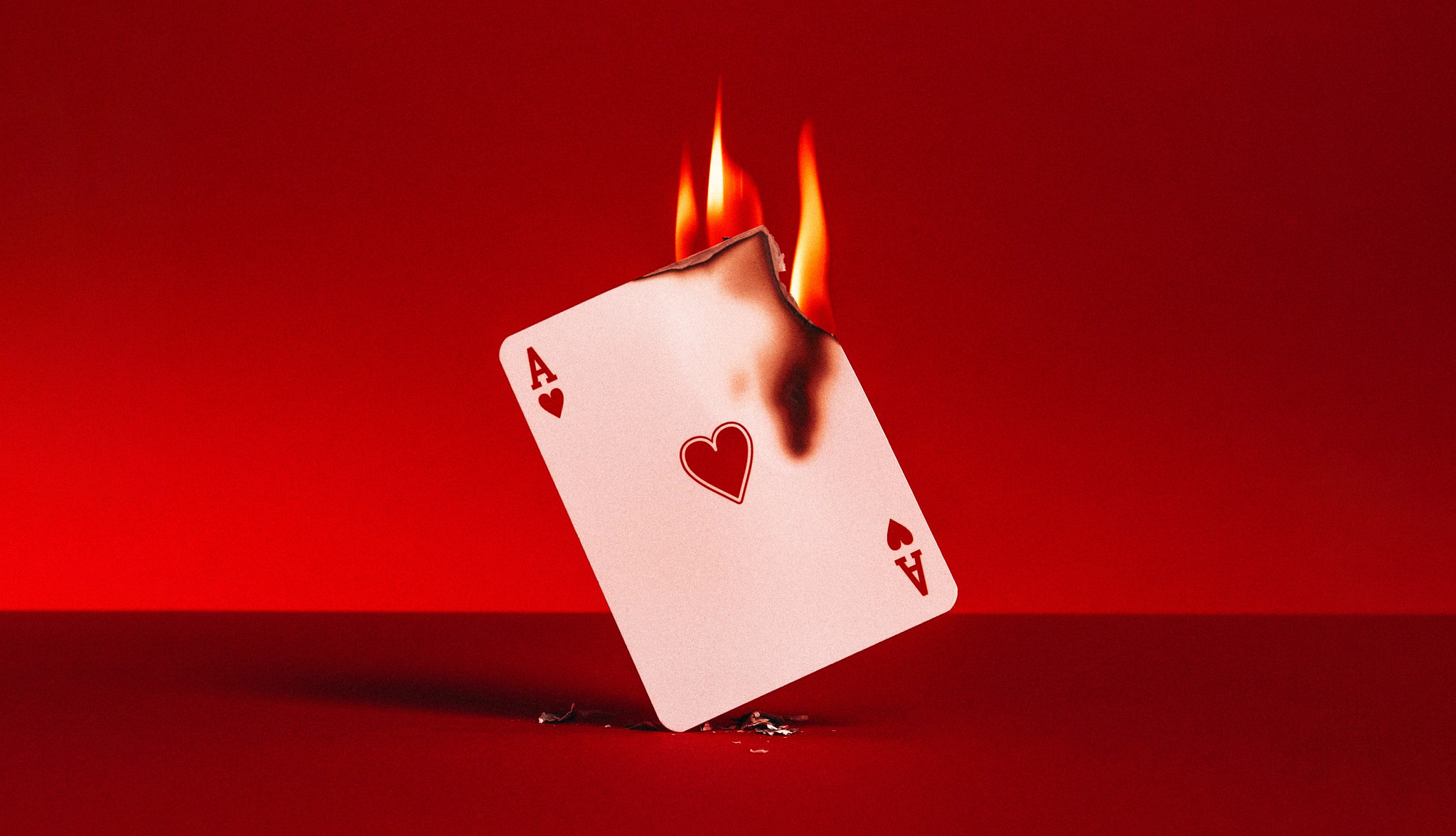 ace of hearts card on fire on red background