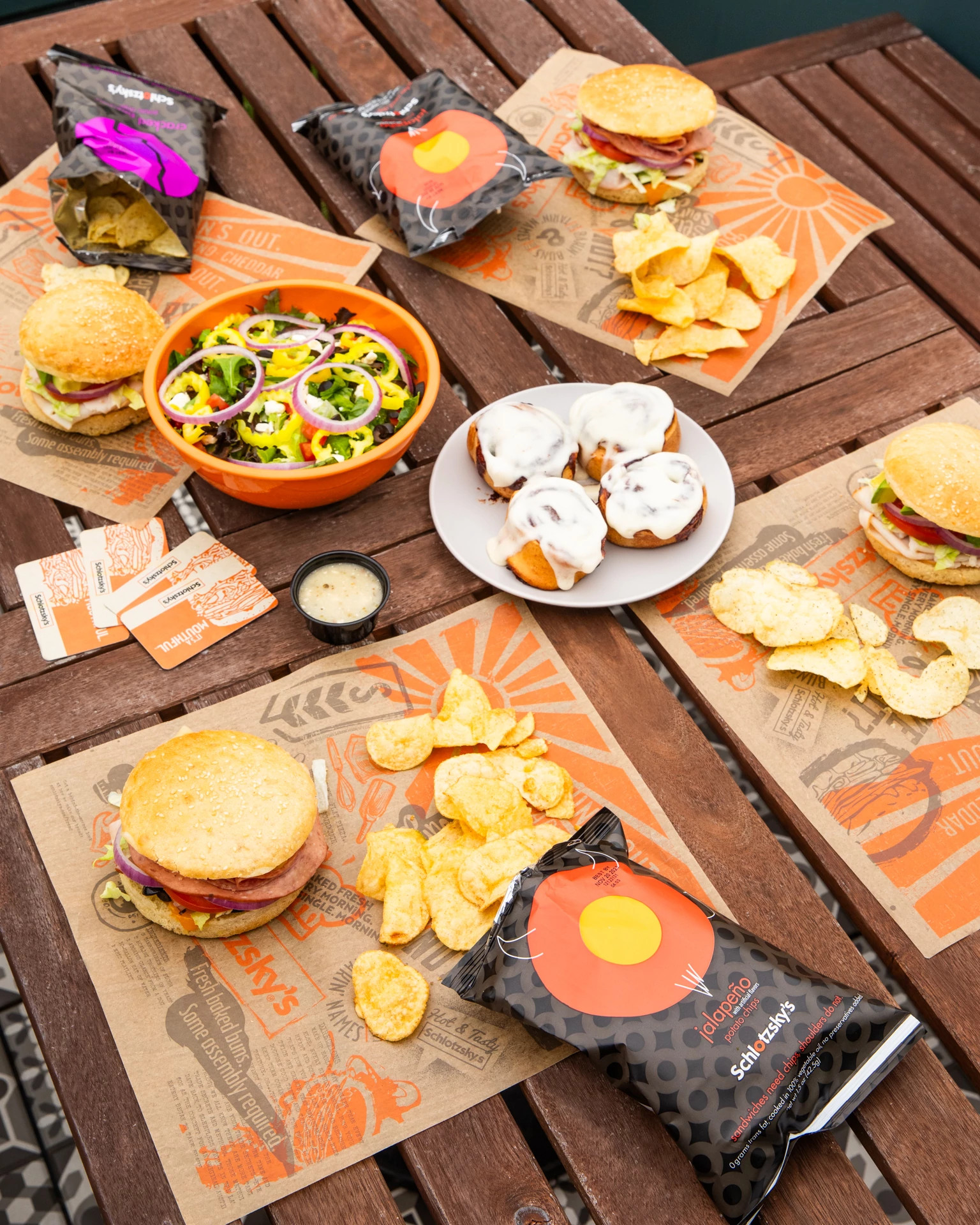 Bocadillos Schlotzsky's, papas fritas y postre en una mesa de pícnic