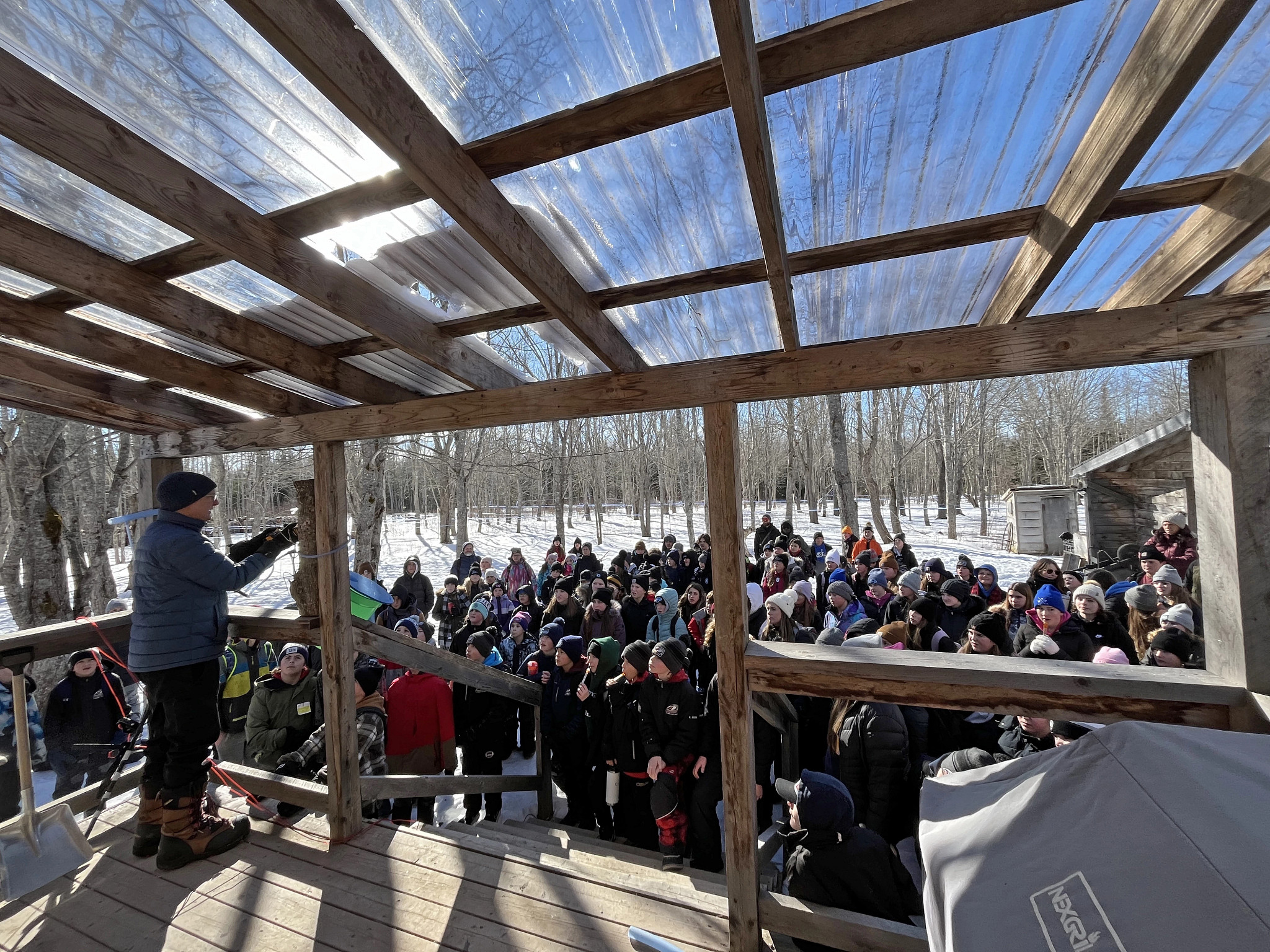 a large crowd gathering for a tour at a maple farm