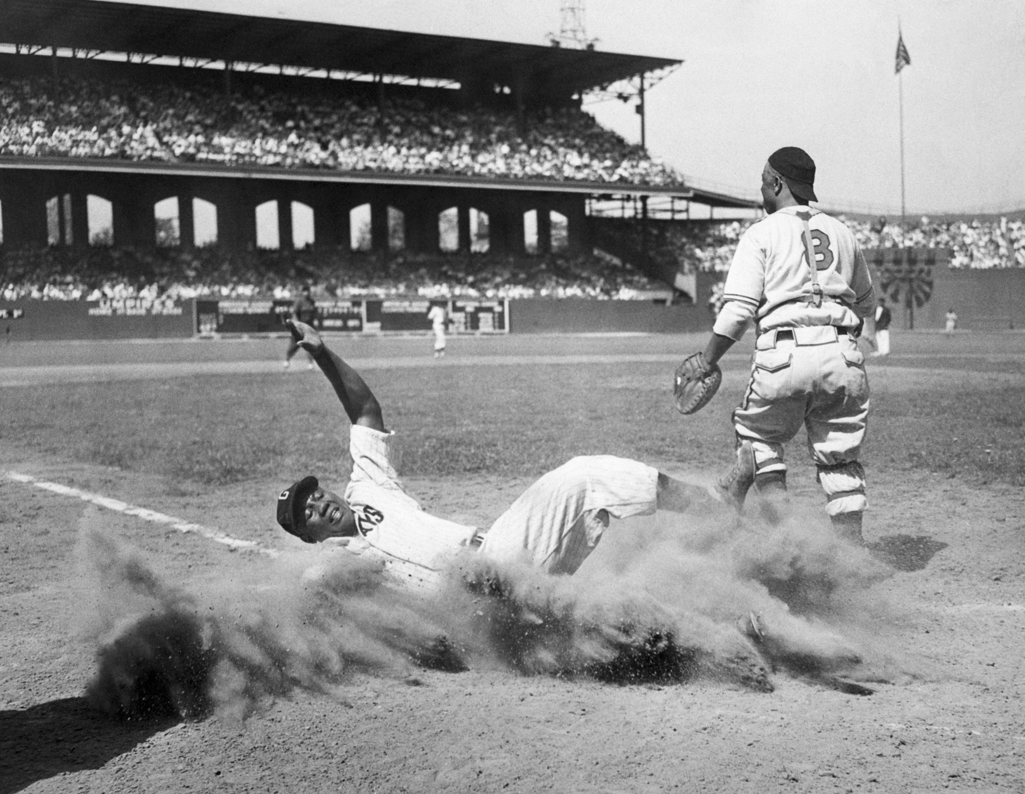 baseball player josh gibson slides into home plate during a game