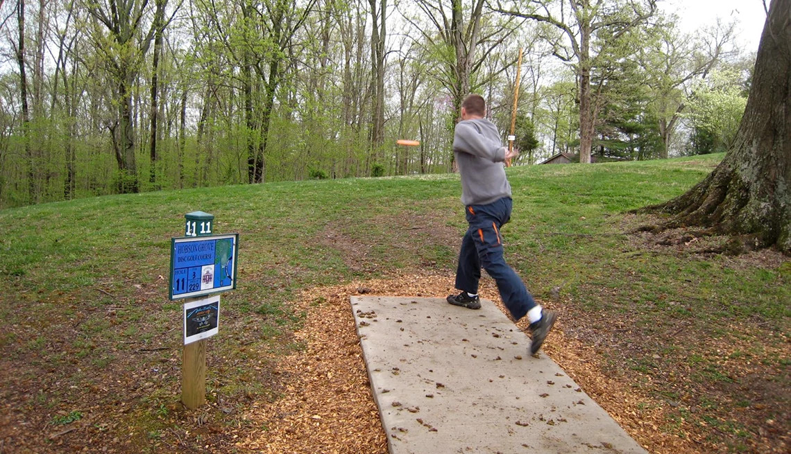 a man throwing a disc at a disc golf course