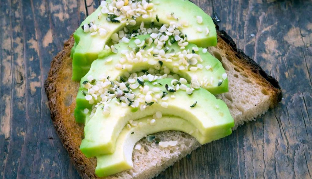 Eating avocados can promote a healthy brain and overall health Toasted bread with avocado, cress and hemp seeds on wood