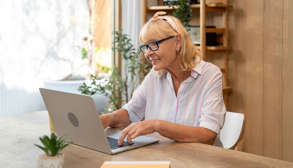 A smiling woman sits at a laptop